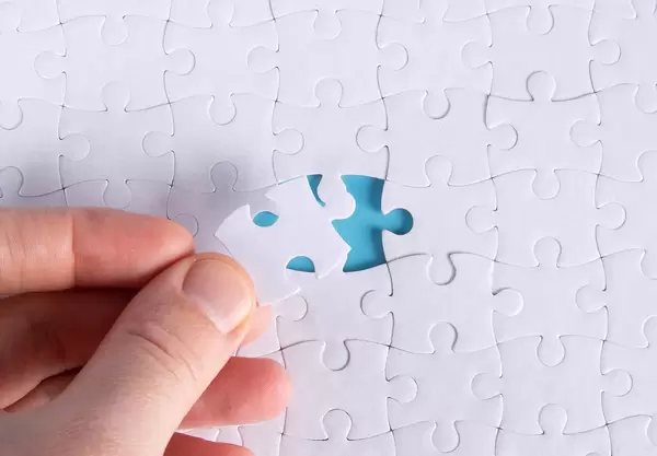 Hand with missing jigsaw puzzle piece. Business concept image for completing the final puzzle piece