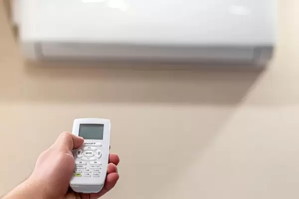 Hand with remote control directed on the conditioner