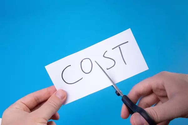 Hand with scissors cutting a paper with Cost text