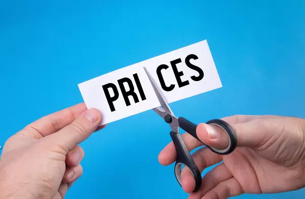 Hand with scissors cutting a paper with Prices text