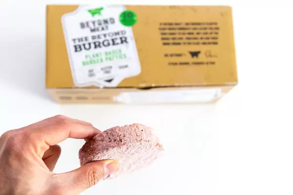 Hand zeigt Beyond Meat Patty als eine gesunde veganische und glutenfreie Alternative zum Burger-Fleisch