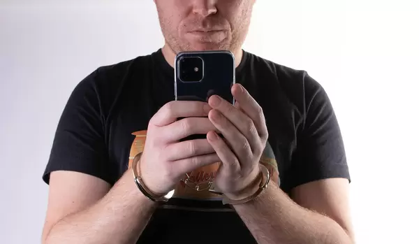 Handcuffed hands with a mobile phone