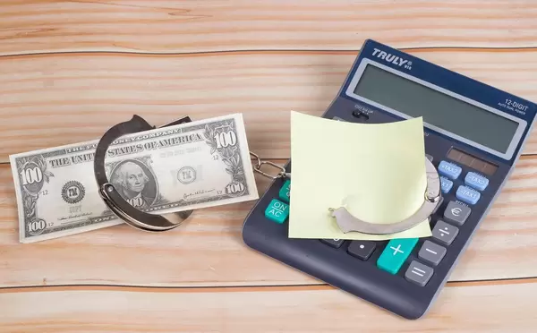 Handcuffs with money, calculator and empty sticky note