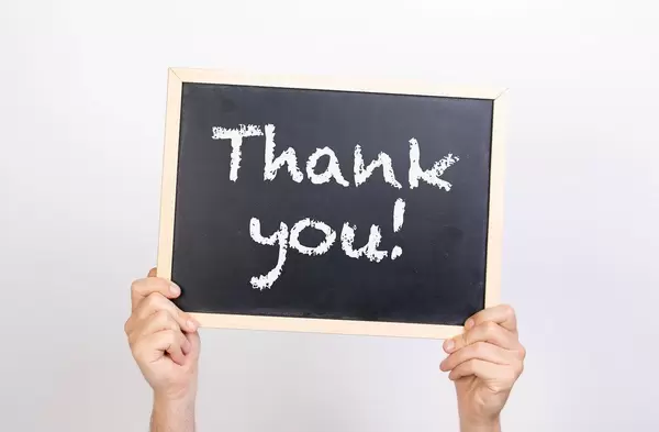 Hände halten eine Kreidetafel hoch, mit dem Text "Thank you" - Dankeschön