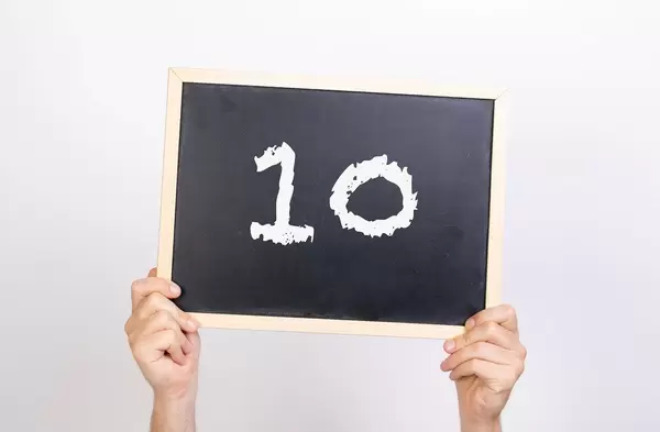 Hände halten eine Kreidetafel hoch, mit der Zahl 10