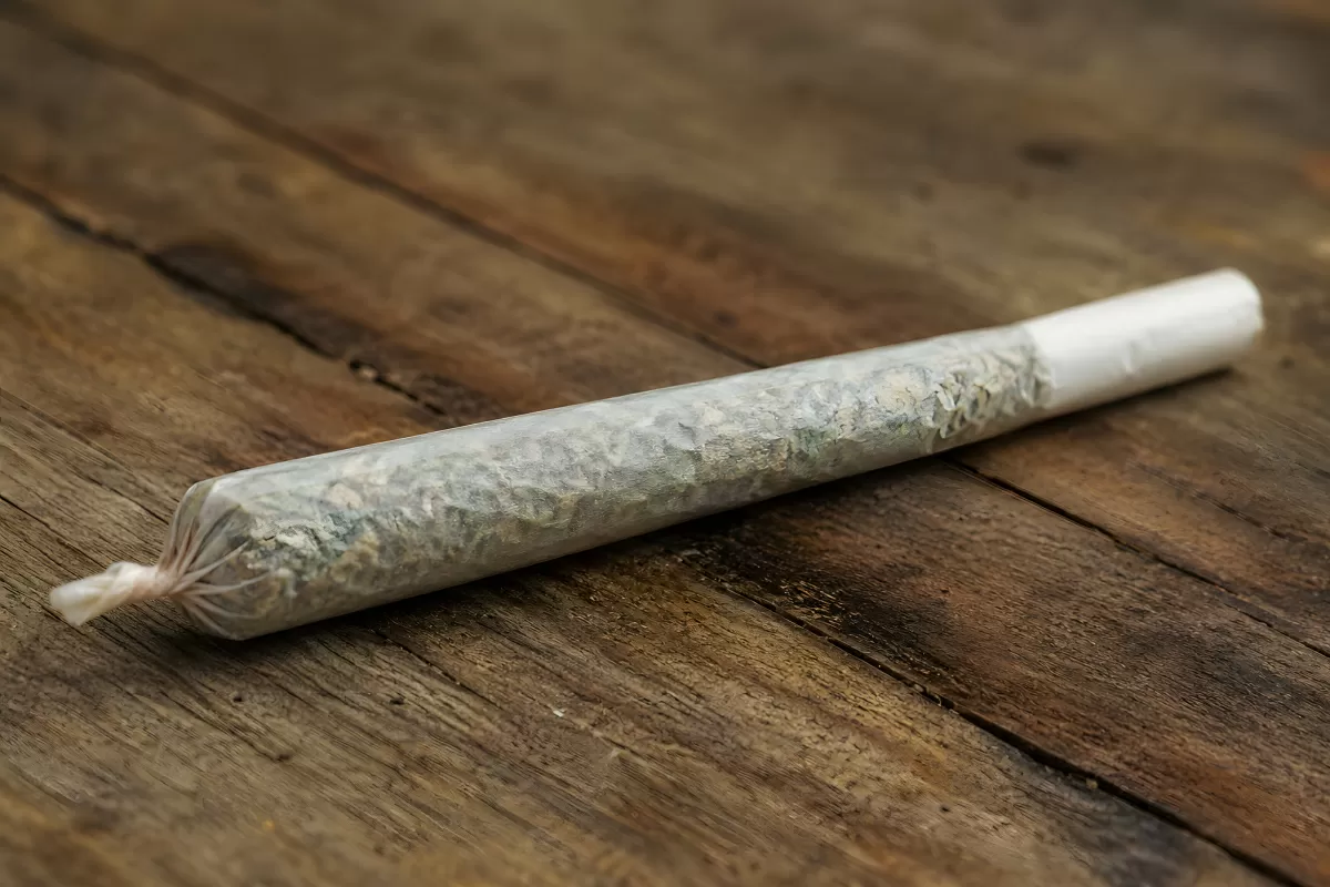 Handgerollter Joint liegt auf rustikalem Holz