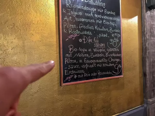 Handgeschriebene Speisekarte mit Empfehlung von einem veganischen Vietnamesischen Gericht 'Dau hu sot cam'