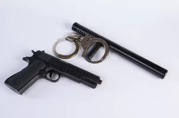 Handgun with rubber baton and handcuffs on a white background