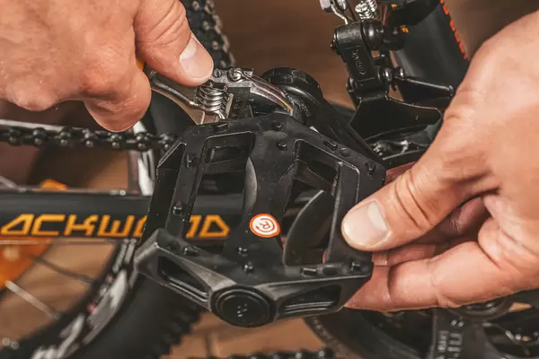 Hands fix the pedal with a wrench, assembling the bike