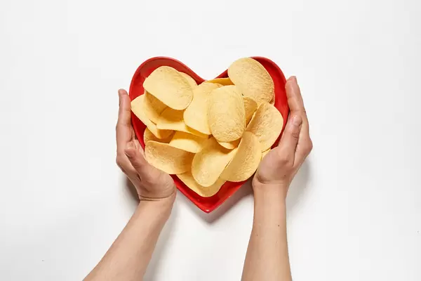 Hands hold heart-shaped plate full of crispy salty chips