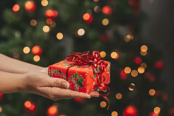 Hands holding a red christmas gift on bokeh background