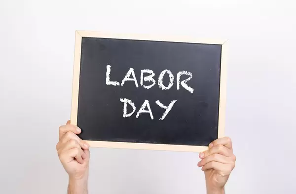 Hands holding blackboard with text Labor Day