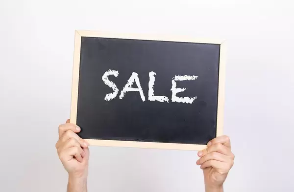 Hands holding blackboard with text Sale