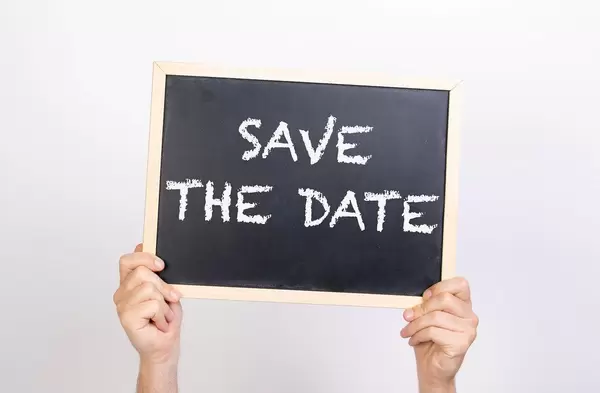Hands holding blackboard with text Save the date