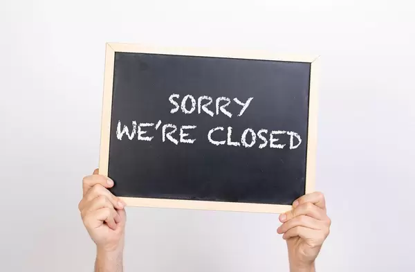 Hands holding blackboard with text Sorry we're closed