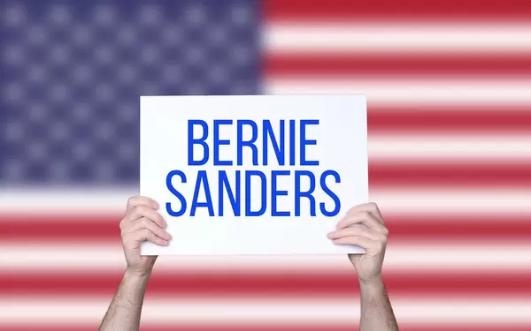 Hands holding board with Bernie Sanders text with USA flag background