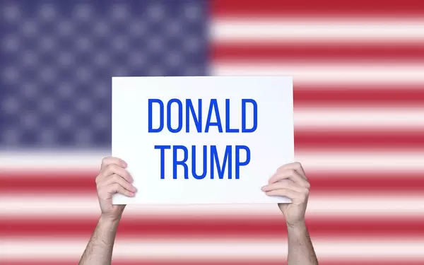 Hands holding board with Donald Trump text with USA flag background