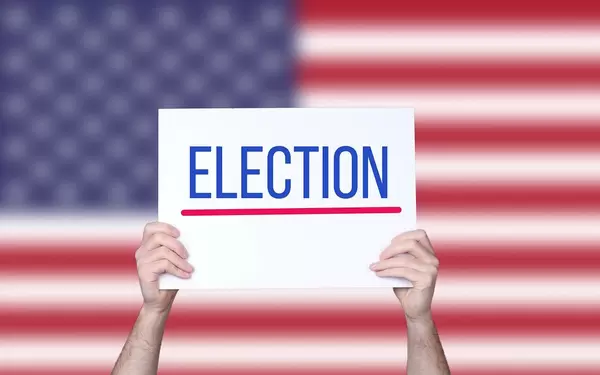 Hands holding board with Election text with USA flag background.jpg