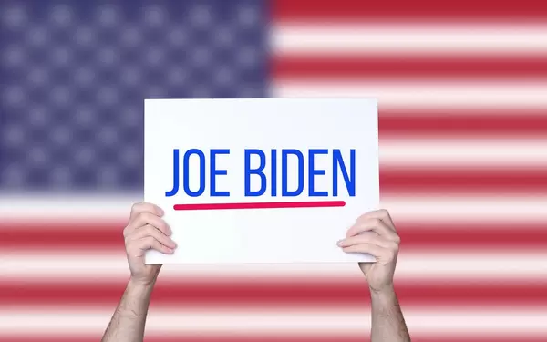 Hands holding board with Joe Biden text with USA flag background