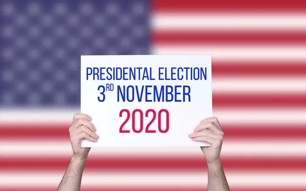 Hands holding board with Presidental Election 2020 date with USA flag background