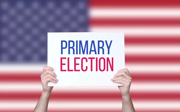 Hands holding board with Primary Election text with USA flag background.jpg