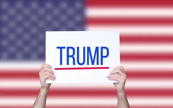 Hands holding board with Trump text with USA flag background.jpg
