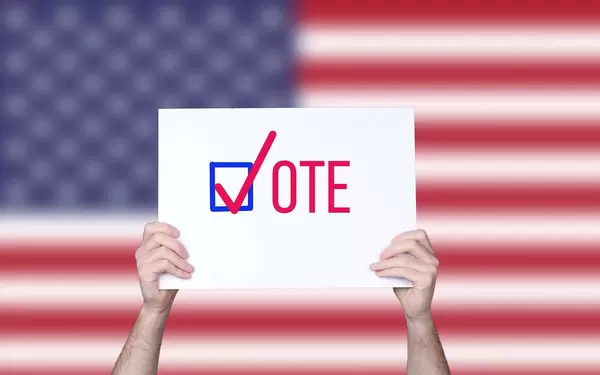 Hands holding board with Vote concept with USA flag background