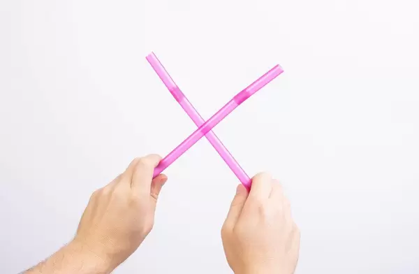 Hands holding two drinking straws