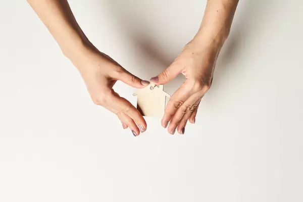 Hands holding wooden flat house against white background