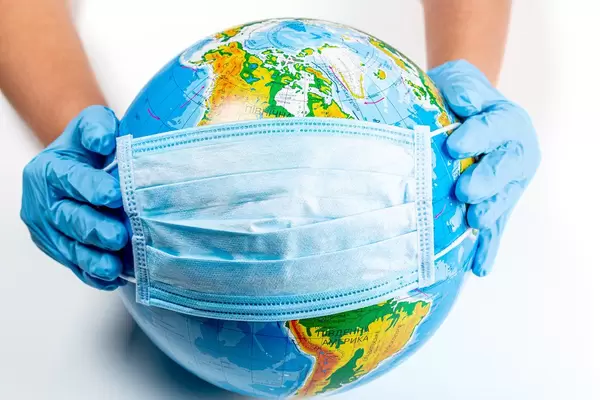 Hands in gloves hold a globe in a medical mask. The concept of the fight against coronavirus in the world