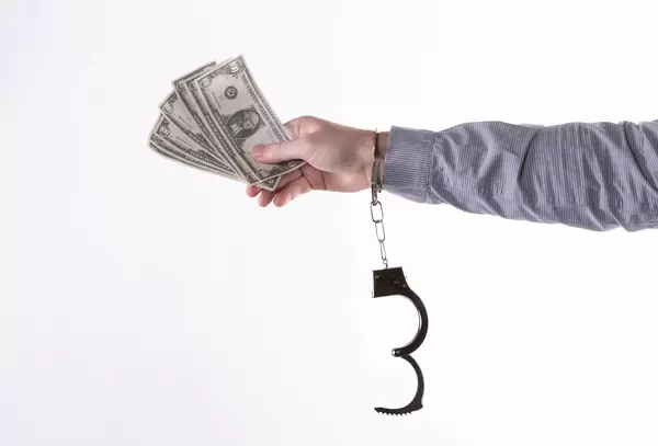 Hands in handcuffs with money