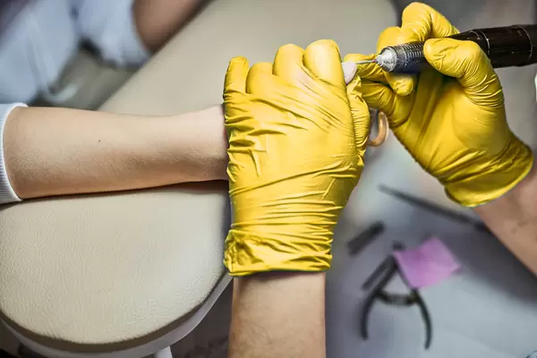 Hands manicurist with tool. Manicurist in gloves removes cuticle