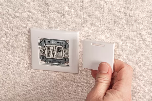 Hands of a man working with an electric light switch