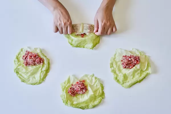 Hands of a woman preparing stuffed cabbage rolls - home cooking concept