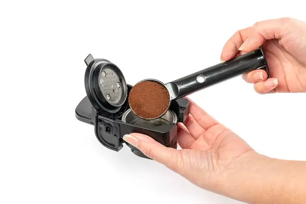 Hands pouring ground coffee into the filter for the coffee machine