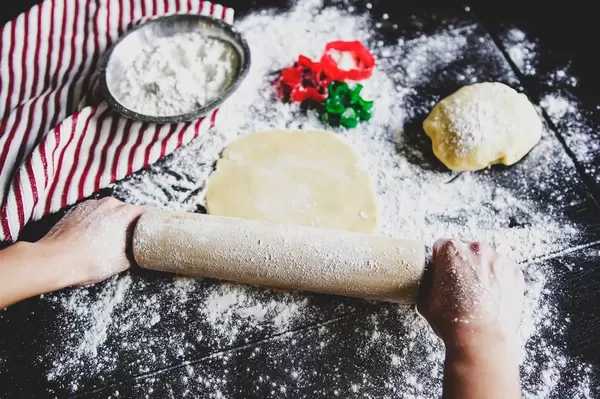 Hands rolling cookie dough on a wooden table