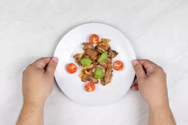 Hands serving Fried Chicken Liver served on the plate
