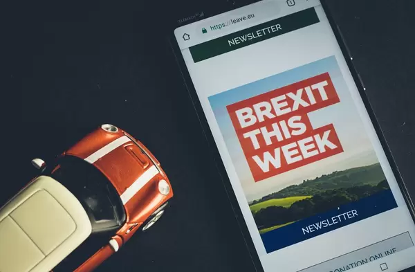 Handy zeigt "Brexit This Week" - Newsletter der leave.eu Website, neben britischem Spielzeug-Auto