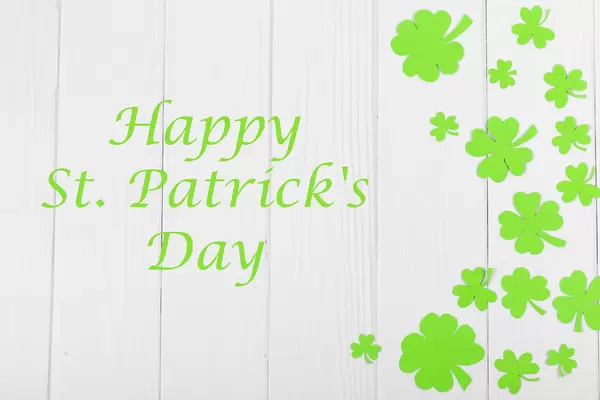 Happy saint patrick's day greeting card with traditional symbol-shamrock and four-leafed clover on wooden background