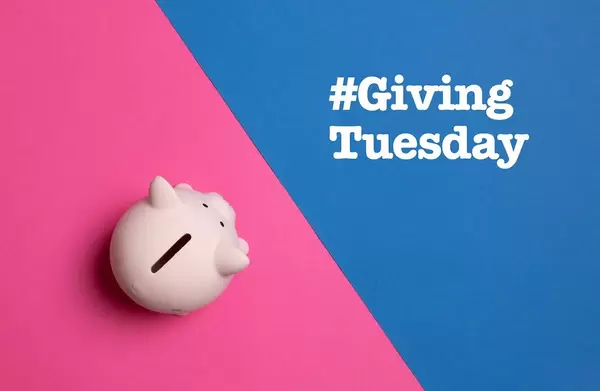 Hashtag der globalen Bewegung #GivingTuesday nach Thanksgiving, für mehr soziales Engagement, neben rosa Sparschwein, auf buntem Hintergrund