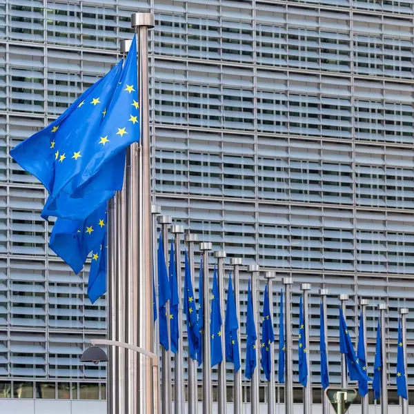 Hauptsitz der Europäischen Kommission in Brüssel mit Flaggen der Europäischen Union im Vordergrund