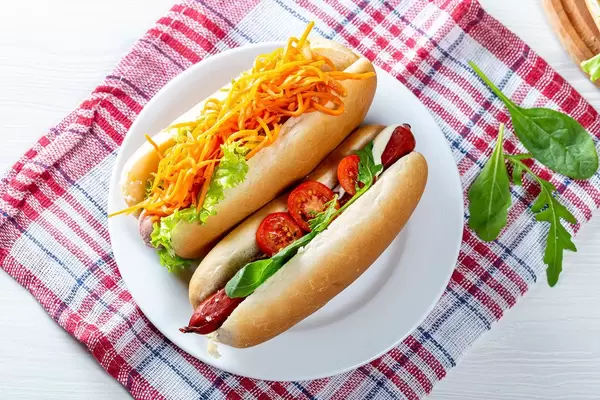 Hausgemachte Hotdogs mit frischen Zutaten, auf einem Geschirrtuch auf dem Küchentisch