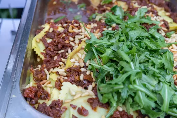 Hausgemachte Ravioli mit Spinat gefüllt, dazu getrocknete Tomaten, Pinienkerne und Rucola