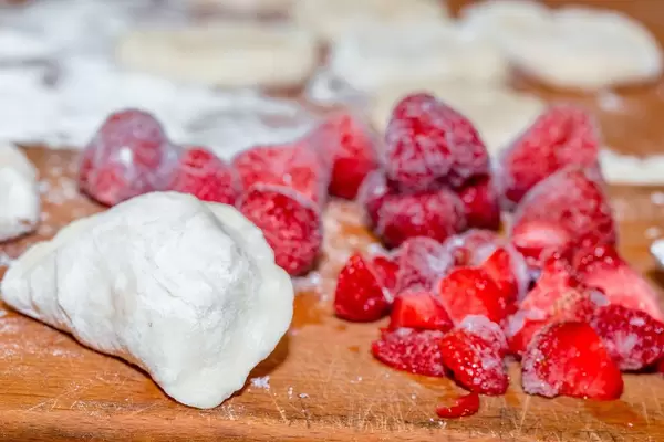 Hausgemachte süße Teigtasche mit gefrorenen Erdbeeren auf Holzbrett