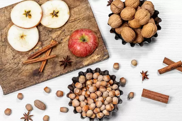 Hazelnuts, walnuts, cinnamon sticks, anise and apples on white wooden background (Flip 2019)