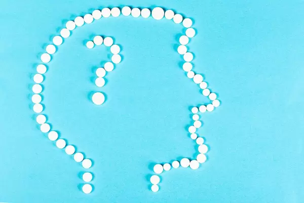 Head of a man with a question mark made from tablets