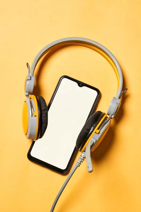 Headphones and smartphone with blank screen on yellow background