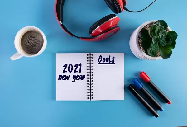 Headphones, flower and notebook with 2021 New Year Goals text