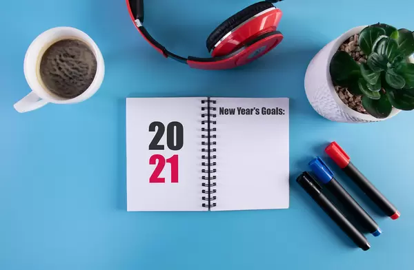 Headphones, flower and notebook with 2021 New Year's Goals text