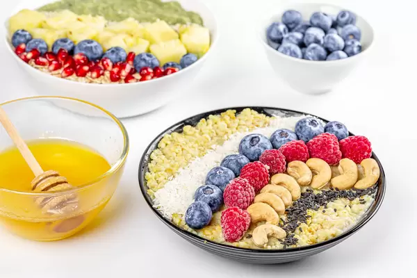 Healthy and tasty food background - porridge with fruits, nuts and seeds on a white background with honey